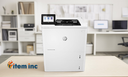 HP LaserJet Enterprise M609 printer on a desk in a modern office setting, with the Item Inc. logo in the corner.