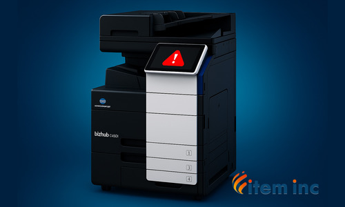 Konica Minolta bizhub C450i multifunction printer on a blue background with a red warning icon on its touchscreen and the Item Inc. logo in the corner.