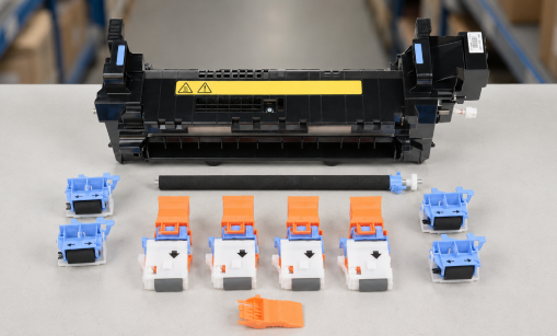 HP printer maintenance kit contents laid out on a workbench: fuser assembly, transfer roller, paper pickup rollers, and separation rollers